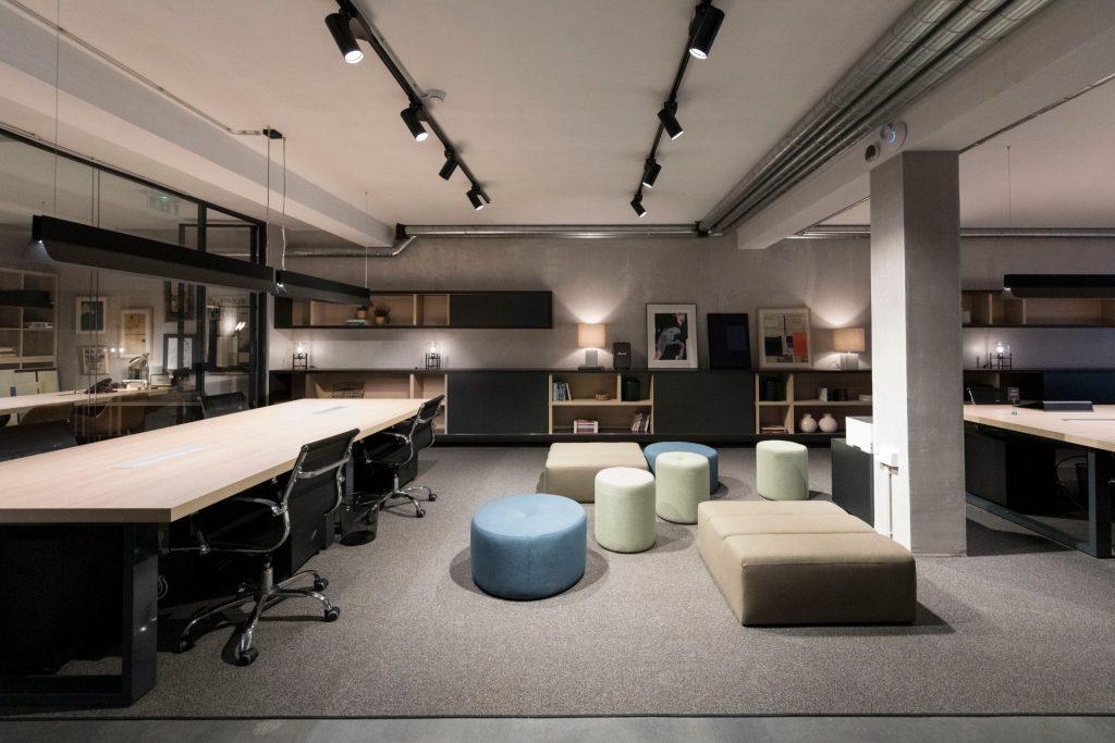 Área de open space e lounge no Outglocal Coworking Aveiro, com puffs coloridos, estantes de design e secretárias.