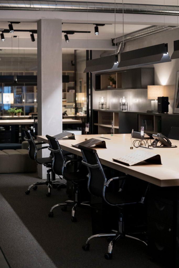 Plano aproximado de uma mesa de trabalho partilhada no Outglocal Coworking Aveiro, equipada com telefones e cadeiras de escritório.