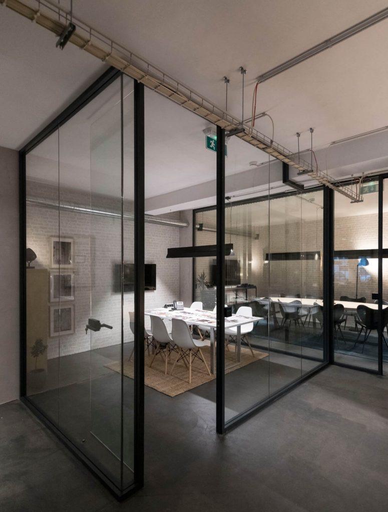 Sala de reuniões envidraçada no Outglocal Coworking em Aveiro, equipada com uma longa mesa branca e cadeiras para equipas.